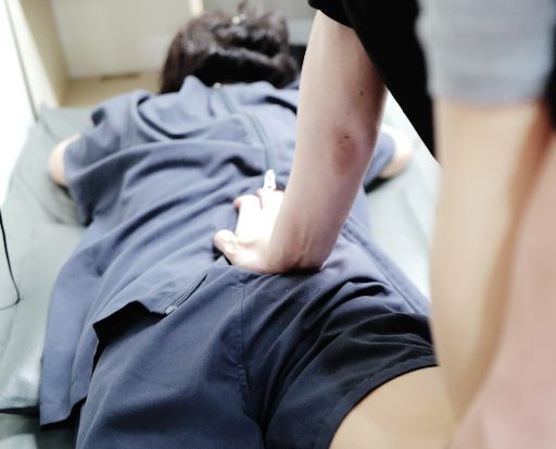 엎드린 환자의 허리에 추나 교정을 적용하는 장면