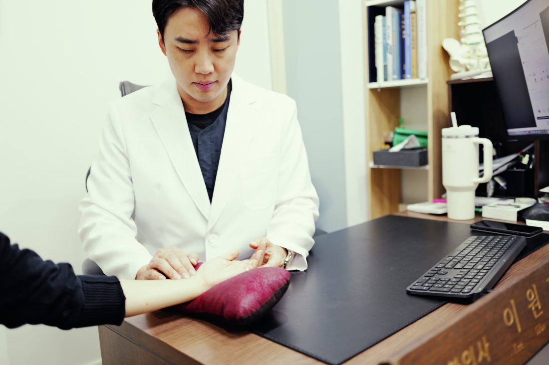 원장이 손목에 손을 얹고 맥을 보는 장면