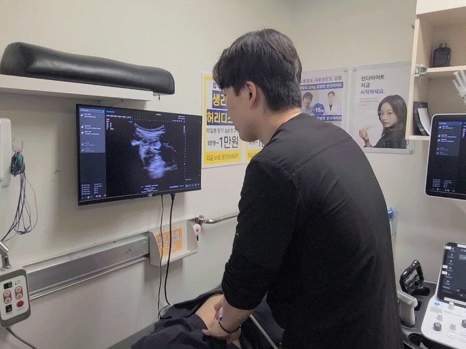 원장이 누운 환자에게 초음파 프로브를 대고 화면을 보는 장면